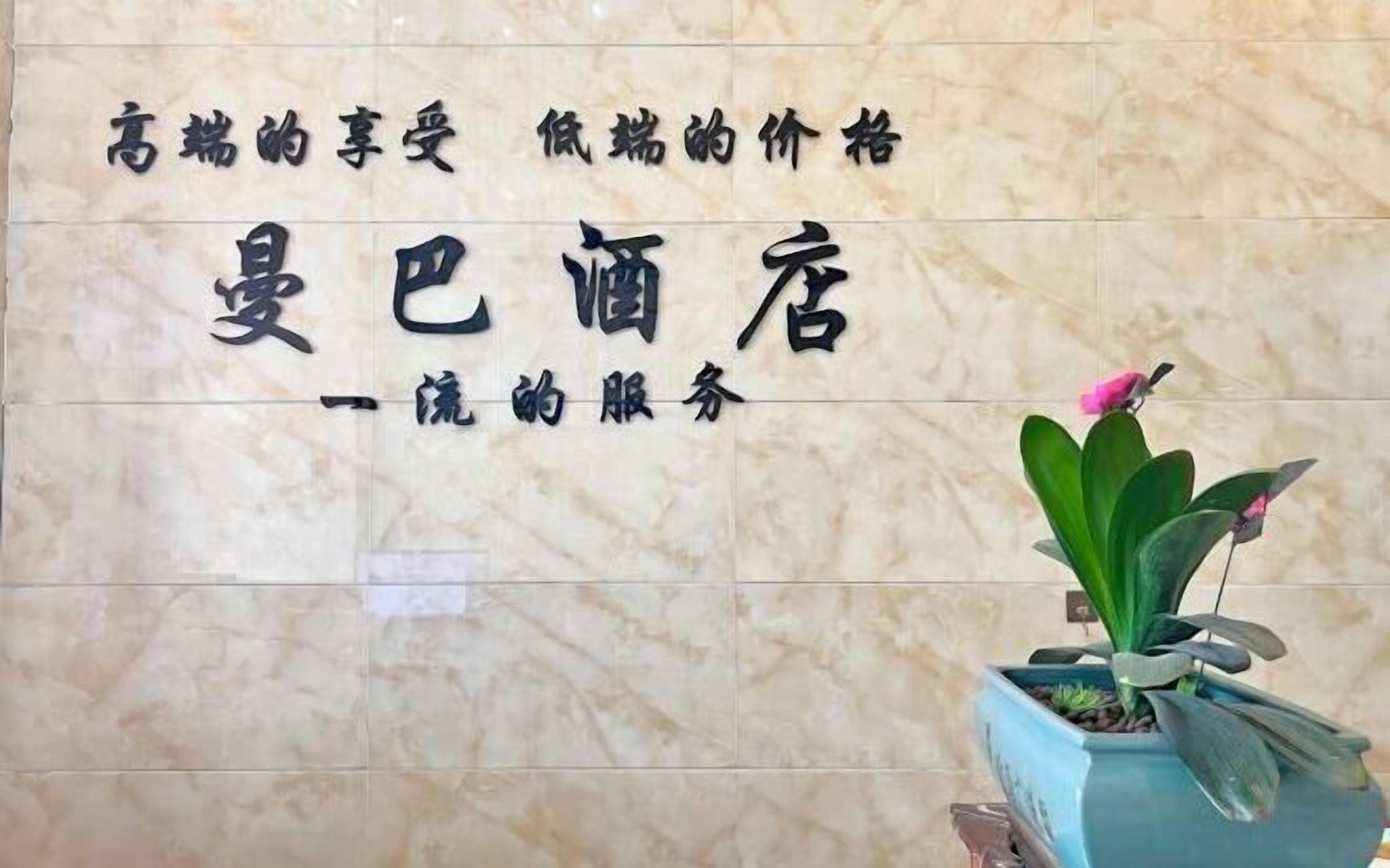 A hotel sign with Chinese characters and a potted plant with a pink flower.
