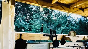 A compact kitchen with a wooden countertop, a stove, a sink, and hanging utensils.