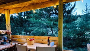 An outdoor wooden deck with a table and chairs, surrounded by trees.