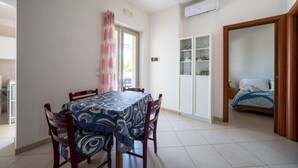 Ein Essbereich mit Tisch für vier Personen, eine Küche mit Schränken und ein Schlafzimmer mit Bett.