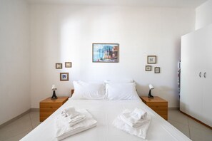 A bedroom with a bed, two nightstands, a wardrobe, and a framed picture on the wall.