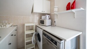 Eine kleine Küche mit Waschmaschine, Mikrowelle und einem Hängeschrank über der Spüle.