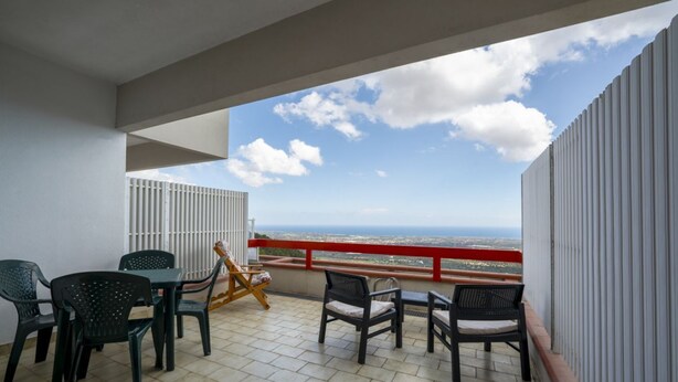 A balcony with a view of the sea, a table with chairs, and a red railing. - Ortensia House: tranquility and sea views in Selva di Fasano (Selva di Fasano)