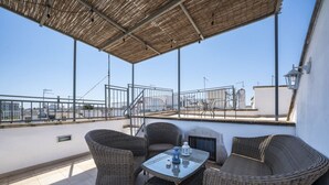 En takterrass med möbler i rotting, ett glasbord och utsikt över stadsbilden.