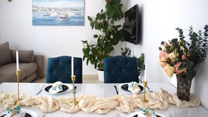 A dining area with a table set for four, a potted plant, and a painting on the wall. - Adriatic Split beach apartment with garden (Podstrana)