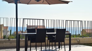 A terrace with a table and chairs, a large umbrella, and a view of the sea. - Adriatic Split beach apartment with garden (Podstrana)
