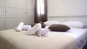 A neatly made bed with rolled towels, a brown pillow, and a white pillow. - Adriatic Split beach apartment with garden (Podstrana)
