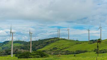 A landscape with multiple wind turbines on a green hill under a cloudy sky.