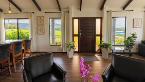 Amplia sala de estar con mesa de comedor, sillas de cuero y un ventanal que ofrece vistas a zonas verdes.