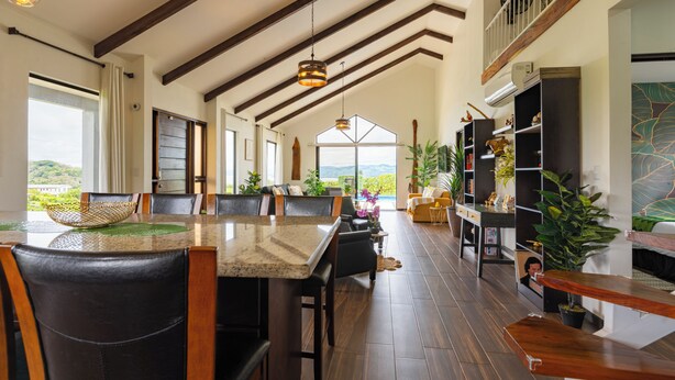 Una cocina amplia con una isla grande, vigas de madera y vistas al exterior.