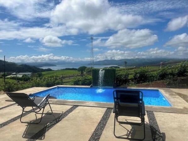 Relax by the serene pool surrounded by lush greenery and rolling hills.