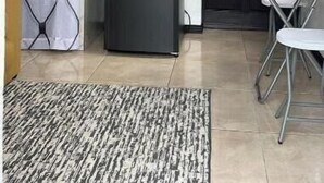 Cocina compacta con refrigerador, pileta y comedor con mesa y sillas.