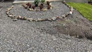 Una casa pequeña y moderna con techo gris y un ventanal grande.