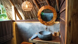 A bathroom with a stone sink, wooden vanity, a round mirror, and a hanging light fixture. - GAELIA BEACH (Santa Marta)