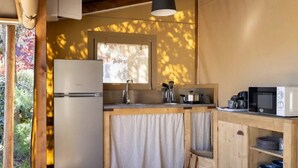 A compact kitchen with a refrigerator, sink, microwave, and wooden cabinets.