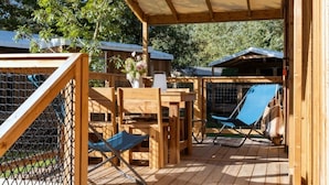 A wooden deck with a covered seating area, a chair, and a table.