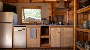A compact kitchen with wooden cabinetry, a built-in dishwasher, and a window providing natural light.