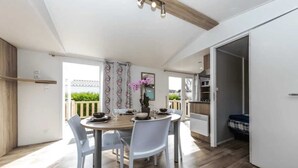 Un comedor moderno con una mesa redonda y sillas blancas, techo de madera y vistas al exterior.