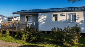 Una casa móvil de un piso con techo de metal, un pequeño porche y un patio cercado.