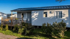 A single-story mobile home with a metal roof, a small porch, and a fenced yard.
