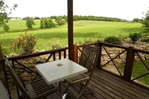 A wooden deck with a table and chairs, overlooking a green field. - ZEcamping 3 étoiles toboggans mobil-home 37m2 4 pers (Inguiniel)
