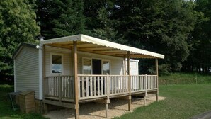 Een kleine blokhut met een houten terras en een overdekte veranda.