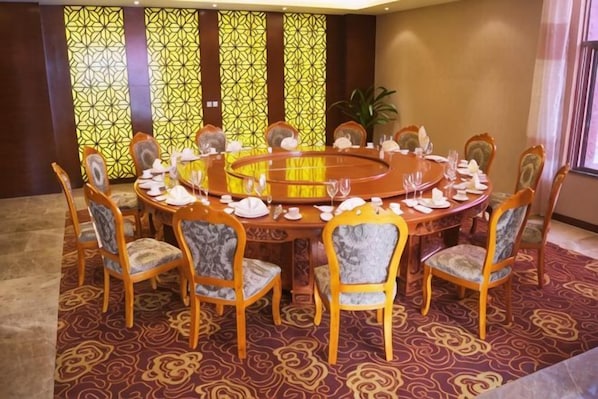 A conference room with a round table, chairs, and a carpeted floor.