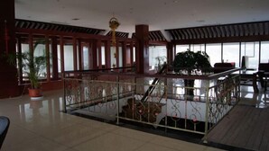 Un vestíbulo espacioso con techo alto, ventanas grandes y una escalera central.