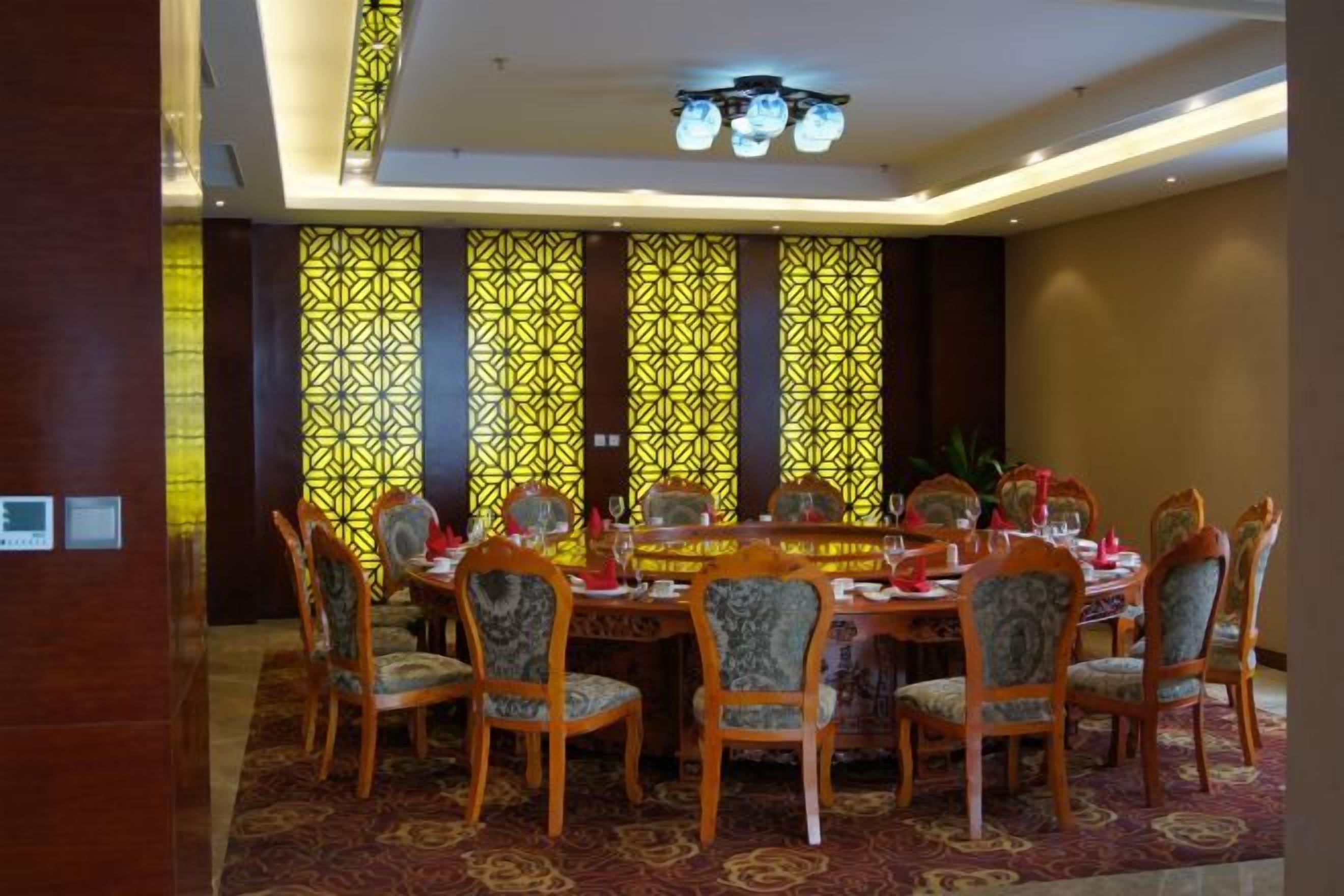 Un espace repas comprenant une table ronde, plusieurs chaises et des décorations murales à motifs.