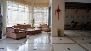 A spacious lobby with a high ceiling, large windows with sheer curtains, and a reception desk with red lanterns. - Weiyuan River International Hotel (Jinggu)