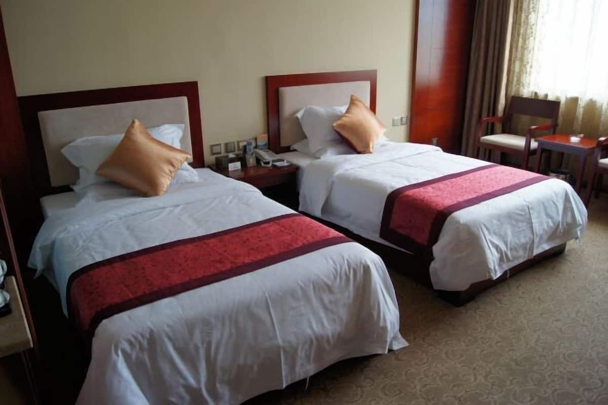 Two double beds with headboards, bedside tables, a chair, and a small table.