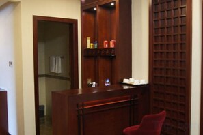 A reception desk with a red chair, a wooden cabinet with items, and a door leading to a bathroom.