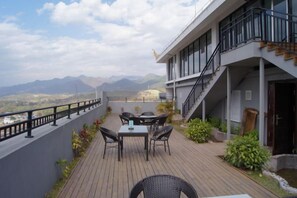Eine Terrasse mit Tisch und Stühlen, eine Treppe und Blick auf Berge.