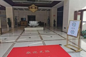 A lobby with a red carpet, a fountain, and a signboard. - Weiyuan River International Hotel (Jinggu)