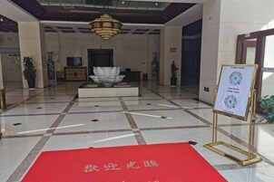 A lobby with a red carpet, a fountain, and a signboard.