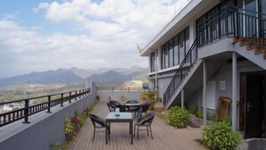 A terrace with a table and chairs, a staircase, and a view of mountains. - Weiyuan River International Hotel (Jinggu)