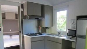 Une cuisine compacte équipée d’une cuisinière à gaz, d’un four à micro-ondes et d’un petit évier.