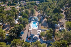 An aerial view of a resort with a swimming pool, RV parking, and a covered area with steps leading to a building.