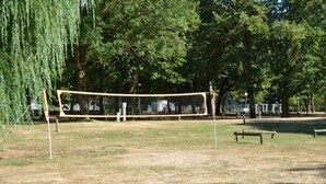 Un filet de volley-ball dans un parc, avec des bancs et des arbres.