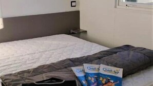Une chambre à coucher avec un lit, une fenêtre et une étagère fixée au mur.