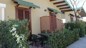 Un patio con una mesa y sillas, un portón de madera, y un edificio con fachada amarilla y vigas de madera.