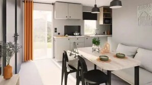 Una cocina moderna con armarios blancos, una mesa de comedor y lámparas colgantes.