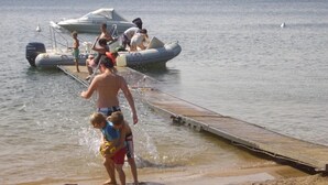 Un muelle que se adentra en un lago con barcos y gente.