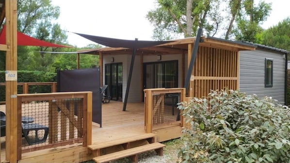 A wooden deck with a covered seating area, a small shed, and a fenced garden area.
