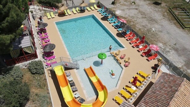 A swimming pool with a slide, sun loungers, and umbrellas.
