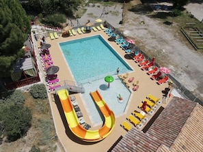 A swimming pool with a slide, sun loungers, and umbrellas.