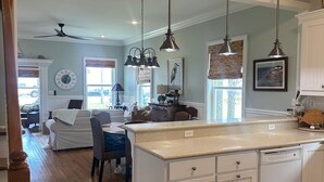 Una cocina amplia con una isla grande, luces colgantes y vistas al comedor.