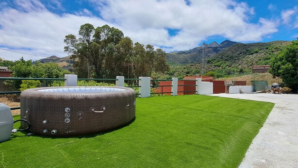A large inflatable pool on artificial grass with a mountain backdrop.