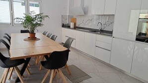 A modern kitchen with a wooden dining table, black chairs, and a potted plant.