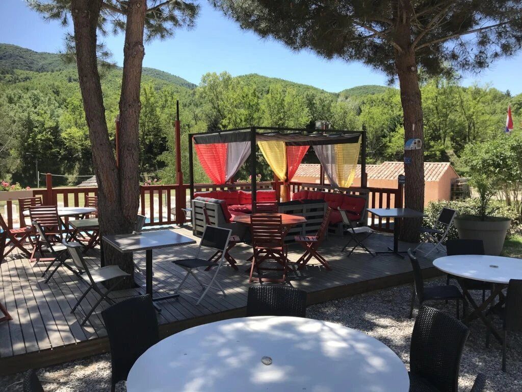 An outdoor patio area with a covered seating area, tables, and chairs.